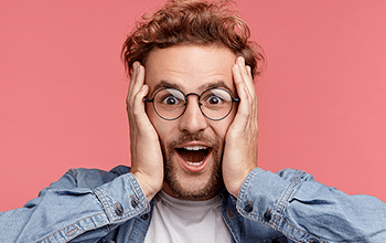 male in glasses holding his head in surprise